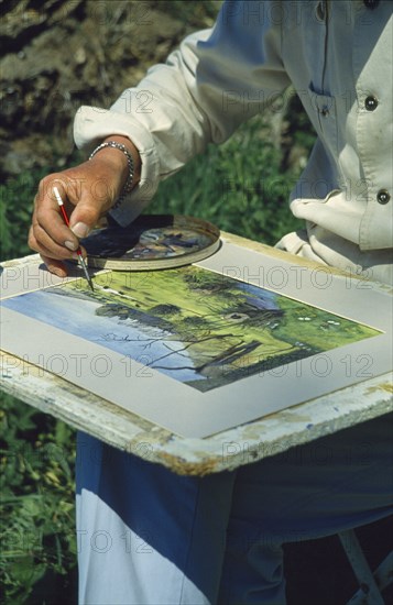 VISUAL ARTS, Painting, Cropped view of an artist painting on a board on his lap