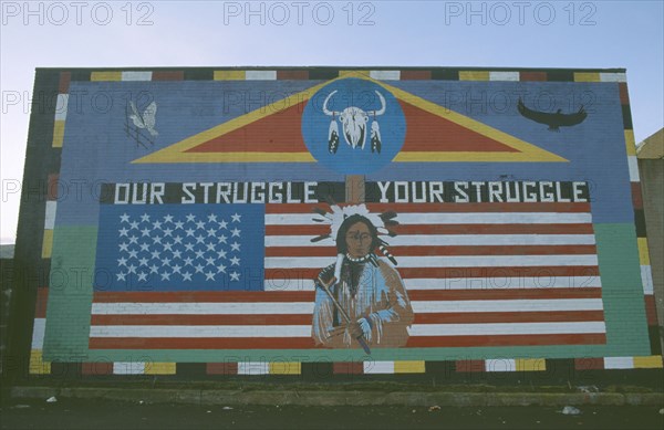 IRELAND,  North , Belfast, "Red Indian mural depicting traditional indian figure standing against the American flag, on Whiterock Road, Belfast"
