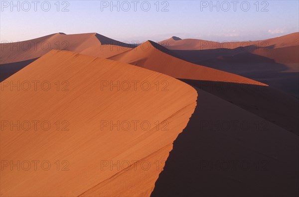 NAMIBIA, Namib Desert, Red sand dunes partially cast in shadow