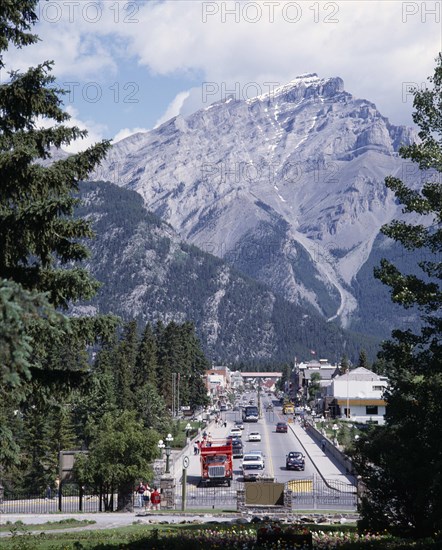CANADA, Alberta, Banff, Banff Avenue the main straight street with a mountain peak behind seen between pine trees