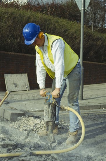 ARCHITECTURE, Construction, Workers, Man wearing ear protection helmet and goggles using pneumatic drill in the road