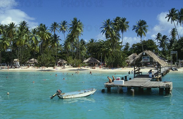 WEST INDIES, Tobago, Pigeon Point, Boat jetty and beach from the sea with tourists sunbathing and swimming
