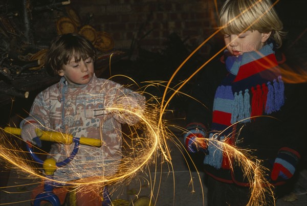 FESTIVALS, Fireworks, Gut Fawkes, Two young children in scarfs and gloves waving sparklers in the air at night