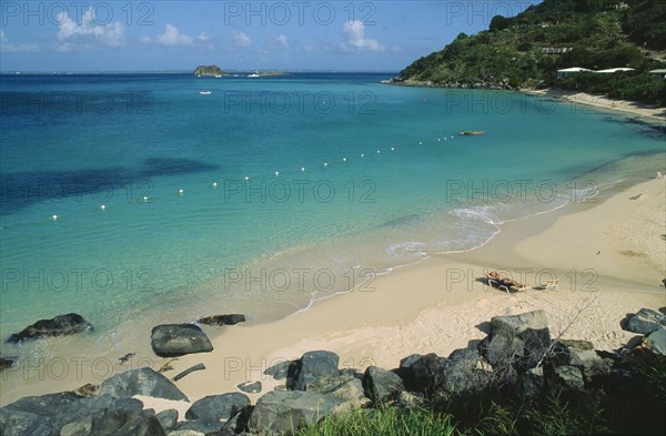 WEST INDIES, St Martin, Grande Case Beach, Wide view of the bay with man sunbathing on sun lounger by the water’s edge