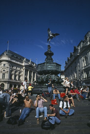 ENGLAND, London, Picadilly Circus with people congregating on the steps surrounding the base of Alfred Gilberts Eros statue dating from 1892