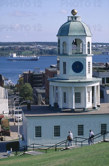 CANADA, Nova Scotia, Halifax, View from hill toward Watch Tower overlooking harbour with sailing ship and people descending steps in the foreground