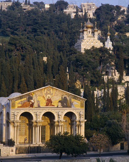 ISRAEL, Jerusalem, Garden of Gethsemane.  Church of All Nations or the Basilica of the Agony with the Church of Saint Mary Magdalene amongst trees on the Mount of Olives behind.