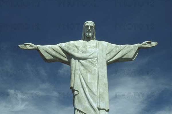 BRAZIL, Rio de Janeiro, Cocovado Statue of Christ the Redeemer with outstretched arms against backdrop of blue sky