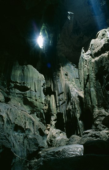 MALAYSIA, Borneo, Niah Caves, View of rocky interior lit by sunlight pouring through small opening in the roof of the cave