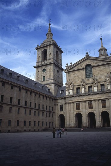 SPAIN, Madrid, El Escorial, Exterior facade of San Lorenzo El Escorial palace and monastery complex with visitors standing in square in the foreground.