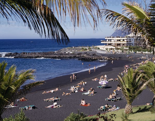 SPAIN, Canary Islands, Tenerife, Playa de la Arena near Los Gigantes with sunbathers on black sandy beach and apartments in the distance