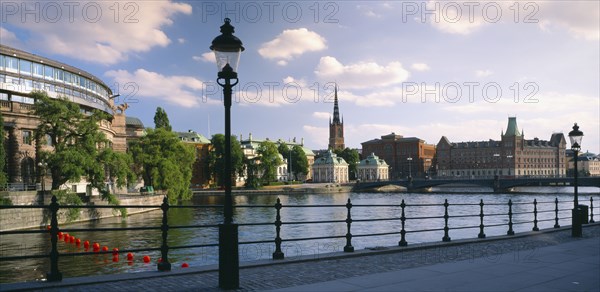 SWEDEN, Stockholm, View from path across water towards waterfront buildings.
