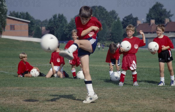 10001961 SPORT Ball Games Football Young boy kicking football during coaching derby.