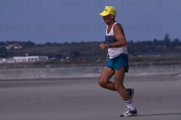 10001965 SPORT  Jogging Jersey . St Ouens Bay. Elderly man jogging on sandy beach