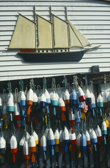 USA, Maine , Boothbay Harbour, Lobster buoys hanging on wall of clapperboard building beneath a model of a three masted sailing ship