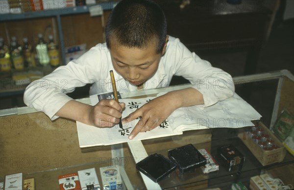 CHINA, Ningxia,  Boy Chinese writing at desk