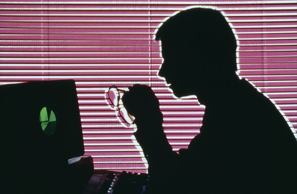 INDUSTRY, Office, Computers, Silhouette of a man on a computer holding glasses and looking at the monitor