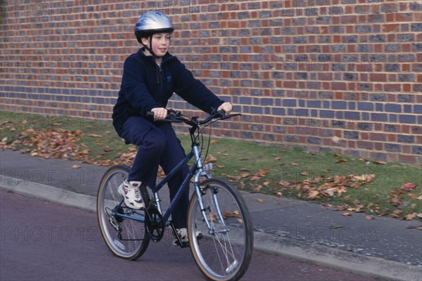 10125394 SPORT  Cycling  Child riding bicycle wearing safety helnet.