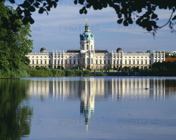 GERMANY, Berlin, Charlottenburg Palace and reflection in lake in the foreground.  Part framed by trees.