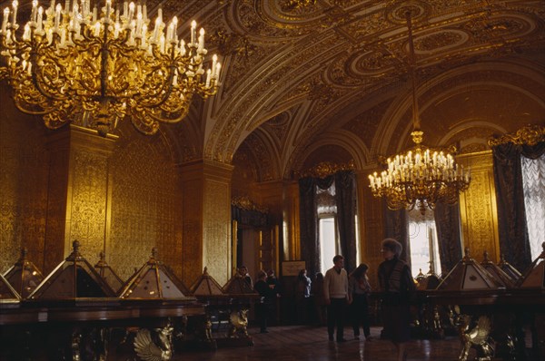 RUSSIA, St Petersburg, "The Hermitage Museum interior, gilted room with display cabinets & visitors"