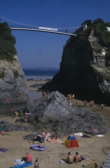 ENGLAND, Cornwall , Newquay, "Partial view of town beach, children play at the foot of two large rocks that a bridge spans"