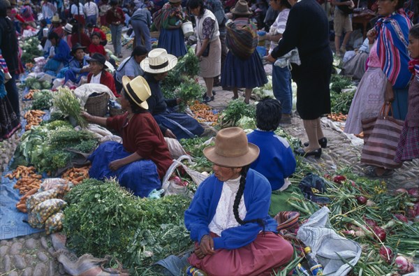 PERU, Cusco Department, Pisac, Vegetable stalls on the ground in cobbled a market place. Crowds of people.