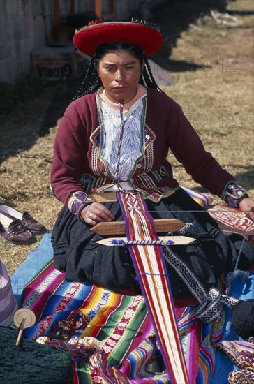 PERU, People, Kneeling woman in traditional costume hand weaving decorative textile.