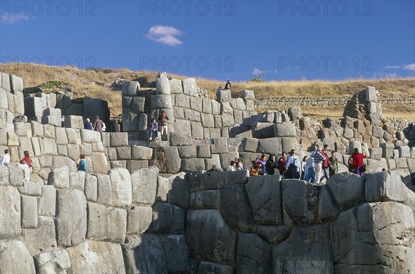 PERU, Cusco Department, Sacsayhuamán, People walking along the top of the Inca walls.