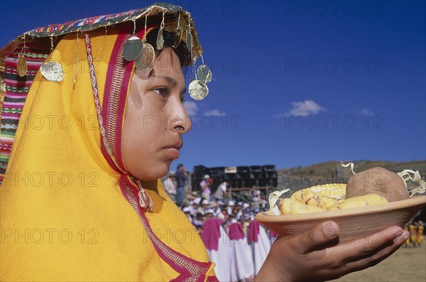 PERU, Cusco Department, Cusco, "Woman in traditional headress carrying an offering of food during Inti Raymi.  Head and shoulders shot, profile to the right. "