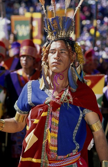 PERU, Cusco Department, Cusco, Male figure in traditional costume and feathered headress at Inti Raymi.  Threequarter shot.