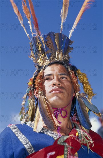 PERU, Cusco, Male figure in traditional costume and feathered headress at Inti Raymi.  Head and shoulders shot. Cuzco