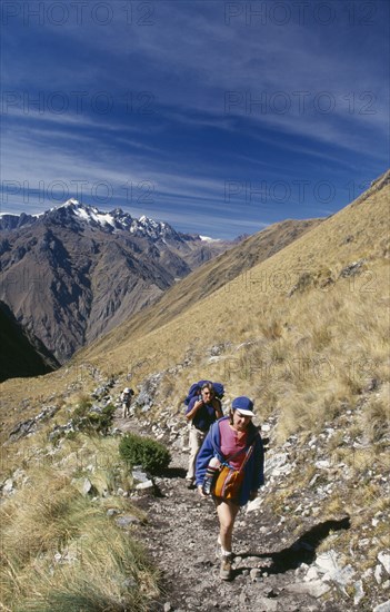 PERU, Cusco Department, The Inca Trail, Treckers with back packs walking up Dead Woman´s Pass.  View towards the mountains behind them.