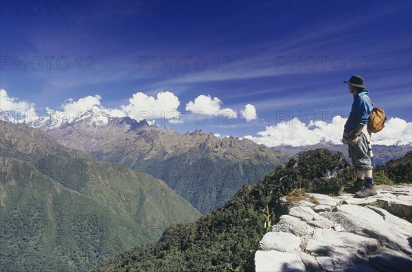 PERU, Cusco Department, Inca Trail, Man standing on high ridge looking out towards the Vilcabamba mountain range near Phuyopatamarca