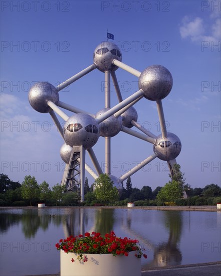 BELGIUM, Brabant, Brussels, The Atomium.  Vast structure of connecting metal spheres reflected in lake in the foreground.