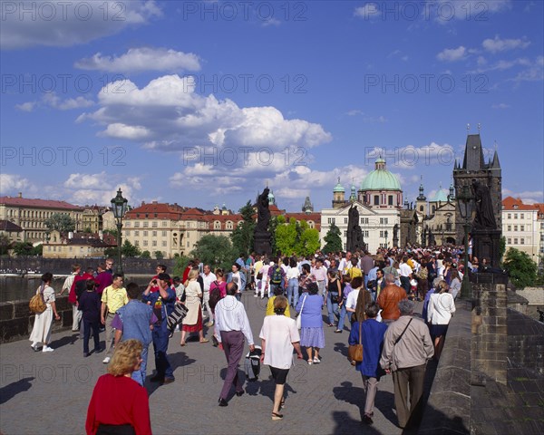 CZECH REPUBLIC, Stredocesky , Prague, Mala Strana.  Crowds of people crossing Charles Bridge.  Typical houses in the background.