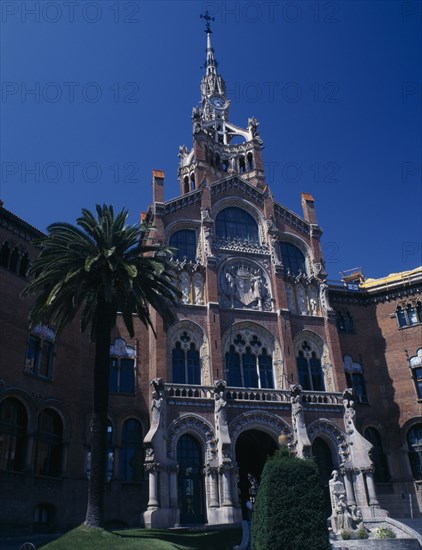 SPAIN, Catalonia, Barcelona, Hospital de Sant Pau designed by Domenech I Montaner.  Ornately carved entrance with arched windows and clock tower.