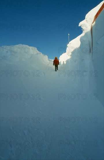 ANTARCTICA, South Pole, "US Amundsen-Scott South Pole Station.  Figure walking through entrance way to the geodesic dome, high banks of drifted snow on either side. "