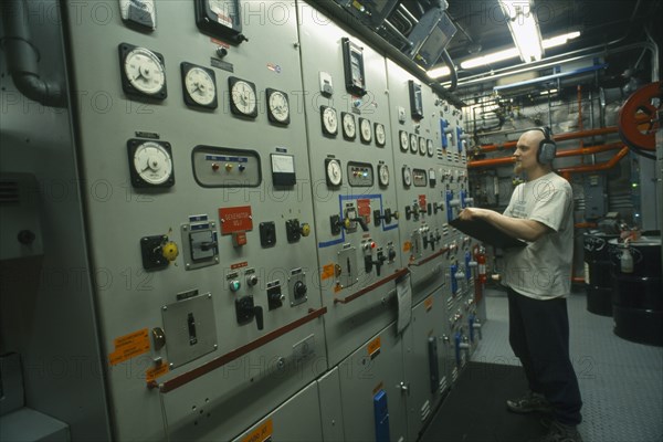 ANTARCTICA, South Pole, US Amundsen-Scott South Pole Station.  Man with clipboard at contol panels in the power plant.