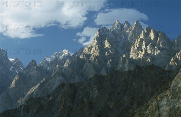 PAKISTAN, Hunza, Karakorum, Jagged peaks of the Karakorum mountain range on the Silk Route with white cloud drifting overhead.