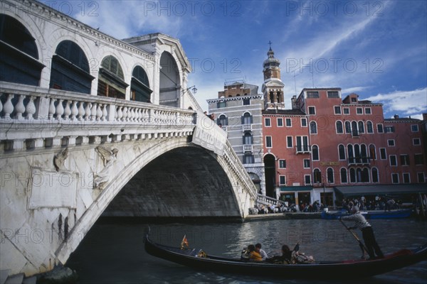ITALY, Veneto, Venice, "The Rialto bridge and a gondola with passengers, the Rialto Hotel in the background."
