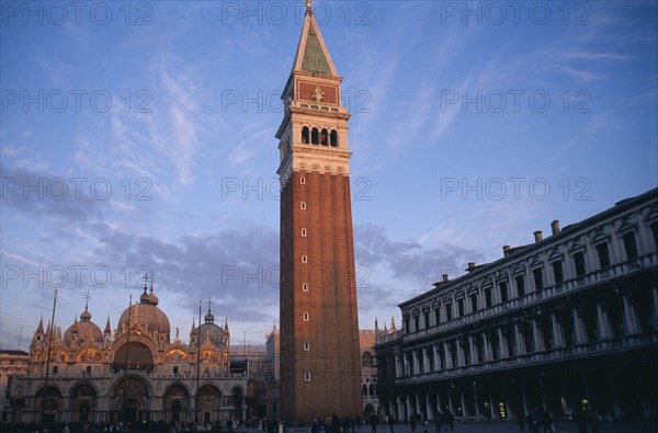ITALY, Veneto, Venice, The Piazza San Marco with the Campanile bell tower in the foreground and the Basilica di San marco behind.  Crowds of people and pigeons.