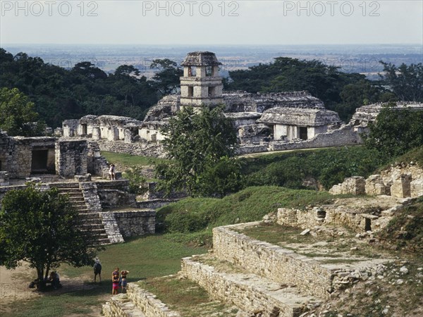 MEXICO, Chiapas State, Palenque, "View over ruins towards the tower of the Palace in Palenque ruins, visitors walking amongst the walls.  "