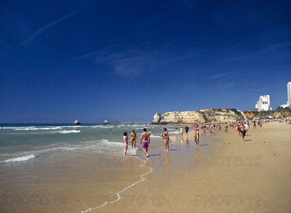 PORTUGAL, Algarve, Praia da Rocha, View along beach with people walking along the waters edge