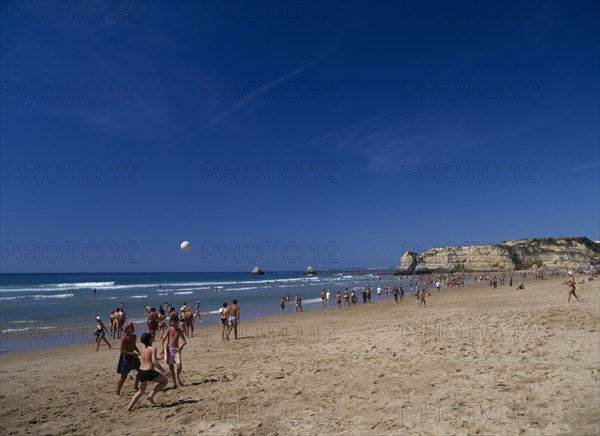 PORTUGAL, Algarve, Praia da Rocha, View along beach with children playing beach football.
