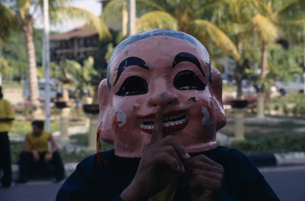 MALAYSIA, Kedah, Langkawi, Masked Chinese New Year Dragon Dance performer with his finger to the mask’s lips requesting silence