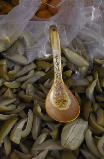 MALAYSIA, Kedah, Langkawi, Spoon in a bowl of green mangoes with vinegar on a stall at the Night Market in Cenang