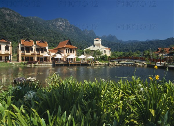 MALAYSIA, Kedah, Langkawi, Oriental Village shopping complex at Burau Bay set around an artificial lake with Gunung Mat Cincang behind