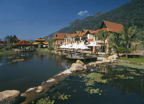 MALAYSIA, Kedah, Langkawi, Oriental Village shopping complex at Burau Bay set around an artificial lake with Gunung Mat Cincang behind