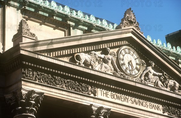 USA, New York , Manhattan, The Bowery Savings Bank Building.  Detail of ornate masonry on roof with clock and the bank’s name carved below.