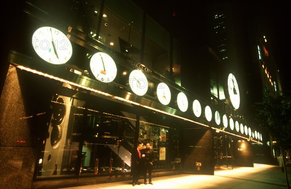 USA, New York , Manhattan, Tourneau Store on West 57th Street at night with row of illuminated clock faces giving the correct time worldwide across the exterior facade.